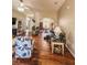 Open living room with wood laminate flooring, neutral walls, floral chairs, and a view into a bright office space at 33818 Venice Ln, Sorrento, FL 32776