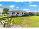 Backyard view showcasing the white exterior, well-maintained lawn, and screened lanai at 3393 Talley Ridge Dr, The Villages, FL 32162