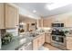 Well-lit kitchen featuring stainless steel appliances, light wood cabinetry, and a cozy breakfast bar perfect for casual dining at 3393 Talley Ridge Dr, The Villages, FL 32162