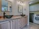 Bathroom featuring double bowl sinks, granite countertops, decorative mirrors, with a laundry room in view at 3432 Fairfield St, The Villages, FL 32162