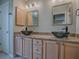 Bathroom featuring double bowl sinks, granite countertops, decorative mirrors, and modern lighting at 3432 Fairfield St, The Villages, FL 32162