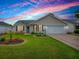Charming single-story home with well-manicured lawn, beautiful garden and a two-car garage under a colorful sky at 3432 Fairfield St, The Villages, FL 32162