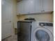 Laundry room with modern front-loading washer and dryer, a laundry sink, and ample cabinet space at 3432 Fairfield St, The Villages, FL 32162