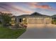 Home exterior at sunset with a three-car garage, a paved driveway, and verdant landscaping at 3745 Causey Ct, The Villages, FL 32163