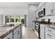 Well-lit kitchen featuring stainless steel appliances, gray cabinets, and light wood flooring at 3745 Causey Ct, The Villages, FL 32163