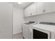 Laundry room with front loading washer and dryer, storage cabinets, and sleek vinyl flooring at 3745 Causey Ct, The Villages, FL 32163