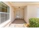 Inviting front porch with neutral tones, manicured shrubs, and a glimpse of natural light through a large window at 403 Duarte Ln, The Villages, FL 32159