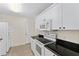 Modern kitchen with white appliances and cabinets, complemented by dark countertops and tiled flooring at 403 Duarte Ln, The Villages, FL 32159