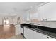 Well-lit kitchen with white cabinets, black countertops, and stainless steel dishwasher at 403 Duarte Ln, The Villages, FL 32159
