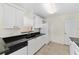 A functional kitchen with white cabinets and appliances, complemented by dark countertops and tiled flooring at 403 Duarte Ln, The Villages, FL 32159