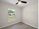 Bedroom features neutral paint, a ceiling fan, wood-look floors and a view of the property at 525 Oak Dr, Tavares, FL 32778