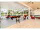 Open concept game room is bright with a pool table, seating, and a view of the lush backyard at 537 Montage Ln, Kissimmee, FL 34759