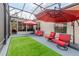 Enclosed patio featuring artificial grass, red cushioned furniture and ceiling with a protective screen at 537 Montage Ln, Kissimmee, FL 34759