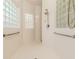 All-white tile shower with glass block windows and handrails for accessibility and safety at 537 Montage Ln, Kissimmee, FL 34759
