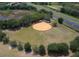 Aerial view of a well-maintained baseball field surrounded by lush greenery and a highway in the distance at 5712 Connors St, Leesburg, FL 34748