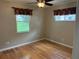 Neutral bedroom featuring hardwood floors, bright windows, and a ceiling fan at 5712 Connors St, Leesburg, FL 34748