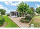 Screened-in lanai with a brick-paved patio, surrounded by lush landscaping and a well-maintained lawn at 616 Hartford Ln, The Villages, FL 32162
