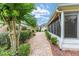 Well-maintained backyard with lush landscaping, featuring a brick-lined walkway and a screened-in porch at 616 Hartford Ln, The Villages, FL 32162