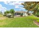 Well-manicured backyard with lush grass, mature trees, and a screened-in patio offering a tranquil outdoor space at 616 Hartford Ln, The Villages, FL 32162