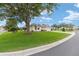 Inviting home with manicured lawn, mature tree, and a brick-paved driveway leading to a two-car garage at 616 Hartford Ln, The Villages, FL 32162