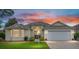 Inviting home exterior featuring lush landscaping, a two-car garage, and brick paver driveway at 616 Hartford Ln, The Villages, FL 32162