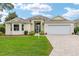 Charming one-story home with a well-manicured lawn, brick driveway, and attached two-car garage at 616 Hartford Ln, The Villages, FL 32162