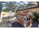 Charming backyard with a playhouse and an entertainment area surrounded by a screened enclosure and lush landscaping at 6750 Sunnyside Dr, Leesburg, FL 34748