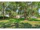 Expansive, tree-lined property showcasing a well-maintained lawn and inviting facade with a charming white stucco home at 6750 Sunnyside Dr, Leesburg, FL 34748