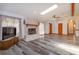 Bright living room featuring a stone fireplace, ceiling fan, and stylish gray wood-look flooring at 6750 Sunnyside Dr, Leesburg, FL 34748