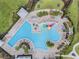 Aerial view of a stunning resort-style pool with a splash pad, seating, and tropical landscaping at 6816 Perch Hammock Loop, Groveland, FL 34736