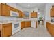 Cozy kitchen includes white tile floors, oak cabinets, and modern white appliances, with an adjoining dining area at 684 Grand Canal Dr, Kissimmee, FL 34759