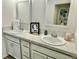 Bright bathroom featuring dual sinks, white cabinets, vanity and modern fixtures at 7394 Lussier Ct, The Villages, FL 34762