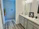 Modern bathroom with a walk-in shower, dual sinks, vanity, and wood-look flooring at 7394 Lussier Ct, The Villages, FL 34762