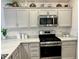 Well-equipped kitchen showcasing stainless steel appliances, light countertops, and grey cabinets for a modern look at 7394 Lussier Ct, The Villages, FL 34762