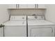 Bright laundry area features a white washer and dryer and overhead cabinets for storage at 802 San Salvador Dr, The Villages, FL 32159
