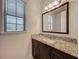 Bathroom vanity with granite countertop, dark wood cabinets, and a large, framed mirror at 8530 Vivaro Isle Way, Windermere, FL 34786