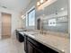 Bathroom featuring dual vanities with dark cabinets, granite countertops, a large mirror, and a glass-enclosed shower at 8530 Vivaro Isle Way, Windermere, FL 34786