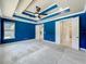 Large bedroom with a tray ceiling, carpet flooring, and multiple doorways, including one to a bathroom at 8530 Vivaro Isle Way, Windermere, FL 34786