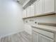 Bright laundry room featuring upper cabinets, lower cabinets and sleek tile floors at 8530 Vivaro Isle Way, Windermere, FL 34786
