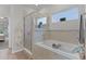 Modern tiled bathroom featuring glass enclosed shower, and large soaking tub, perfect for relaxation at 8978 Se 42Nd Ct, Ocala, FL 34480
