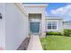 Close-up of front entrance with a teal door, sidelight window, and lush landscaping at 8978 Se 42Nd Ct, Ocala, FL 34480