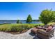 Scenic backyard with lush greenery, stone patio, and comfortable seating overlooking a serene lake at 9648 Weatherstone, Windermere, FL 34786