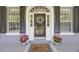 Close-up of the front door adorned with a wreath, flanked by windows and potted plants at 9648 Weatherstone, Windermere, FL 34786