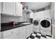 Well-lit laundry room with checkerboard floors, modern washer and dryer, and white cabinets at 9648 Weatherstone, Windermere, FL 34786