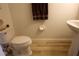 Cozy half-bath with wood-look tile, pedestal sink, toilet, and neutral color scheme at 10115 Regent Park Dr # 2503, Orlando, FL 32825