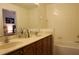 Bathroom featuring a double vanity sink, wood cabinets, and a bathtub with tiled walls at 10115 Regent Park Dr # 2503, Orlando, FL 32825
