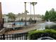 Scenic community pool with a lake view, palm trees, and a black metal fence, perfect for relaxation at 10115 Regent Park Dr # 2503, Orlando, FL 32825
