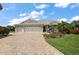 Charming single-story home with manicured lawn, lush landscaping, and three-car garage at 1053 Alcove Loop, The Villages, FL 32162