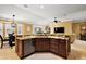Open-concept kitchen island featuring granite countertops, stainless dishwasher, and dark wood cabinets at 1053 Alcove Loop, The Villages, FL 32162