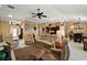 Comfortable living room showcasing recliner seating, a ceiling fan, and an open layout to the kitchen and dining area at 1053 Alcove Loop, The Villages, FL 32162
